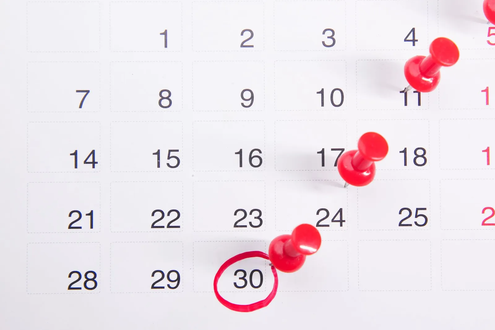 Calendar page with red pushpins and a circled date